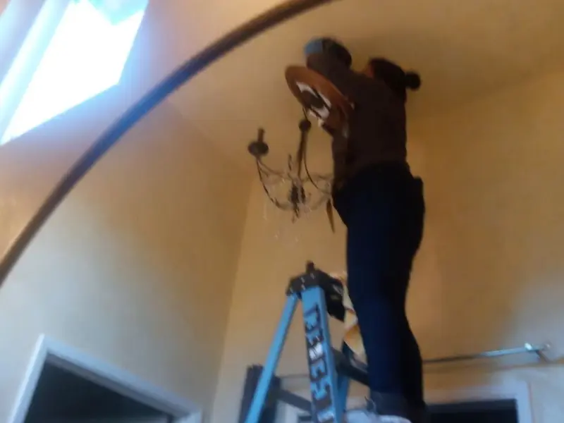 Electrician installing a chandelier in a Del Mar residence